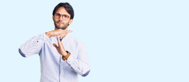 İş gömleği ve gözlük takan yakışıklı İspanyol bir adam. El kol hareketi yapıyor. Hayal kırıklığına uğramış ve ciddi bir yüz ifadesi var. 