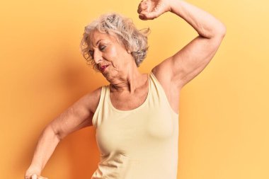 Kıdemli gri saçlı kadın, günlük kıyafetler giyiyor, arkasını yaslıyor, yorgun ve rahat, uykulu ve sabahın erken saatleri için esniyor. 