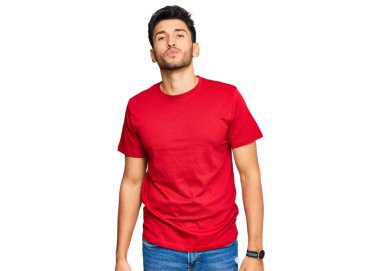 Genç yakışıklı adam, sıradan kırmızı tişörtler giyip kameraya bakıyor ve canlı yayında öpüşüyor. Sevimli ve seksi. aşk ifadesi. 