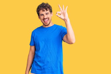 Kıvırcık saçlı, sıradan giyinen, pozitif gülümseyen, el ve parmaklarıyla 