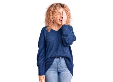 Kış süveteri giyen, kıvırcık saçlı genç sarışın kadın yarı yüz, göz ve ağız kaplamasından yorgun düşmüş. Yüzüm acıyor.. 