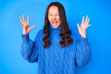 Kış süveteri giyen genç ve güzel bir Çinli kız kolları havada ve gözleri kapalı heyecanla haykırarak başarının çılgınlığını ve çılgınlığını kutluyor. Kazanan konsept 