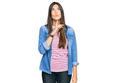 Genç esmer kadın gündelik kıyafetler giyiyordu. Kuşkuya yoğunlaşmıştı. Parmakları çenesinde ve yukarı bakıyordu. 