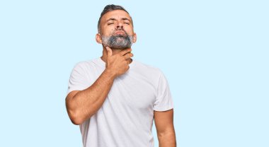 Orta yaşlı, beyaz tişört giyen, boynu ağrıyan, boğazı ağrıyan, grip, mantar ve enfeksiyon kapmış yakışıklı bir adam. 