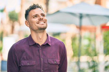 Genç İspanyol adam gülümseyerek şehirde mutlu mesut dikiliyor..