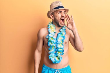 Genç, kel ve mayo giymeyen yakışıklı bir adam ve Hawaii Lei 'si bağırıyor ve ağızdan ağıza bağırıyor. iletişim konsepti. 