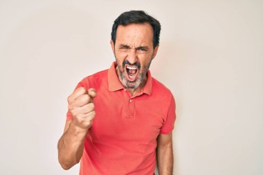 Orta yaşlı İspanyol bir adam, günlük kıyafetler giyiyor kızgın ve kızgın. Öfkeyle bağırırken yumruğunu kaldırıyor. öfke ve agresif konsept. 