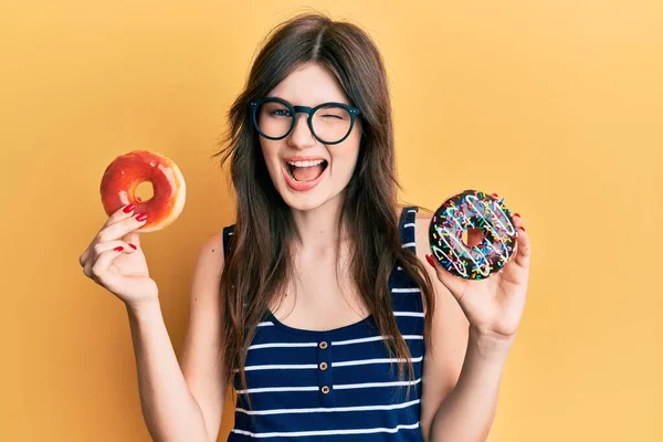 Joven Hermosa Chica Caucásica Sosteniendo Sabrosas Rosquillas Coloridas Guiñando Ojo —  Fotos de Stock