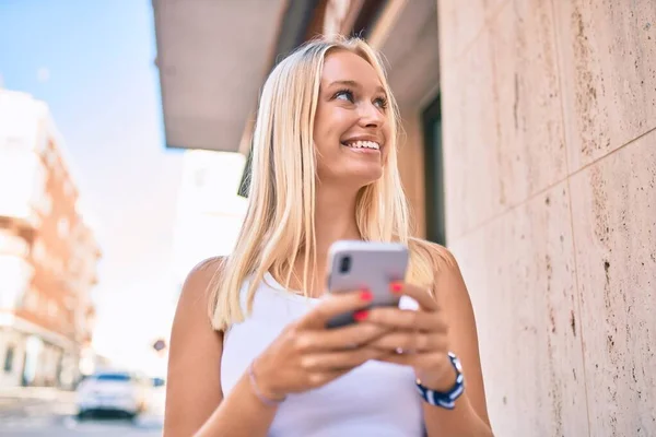 若いですブロンド女の子笑顔幸せな使用スマートフォンで街 — ストック写真