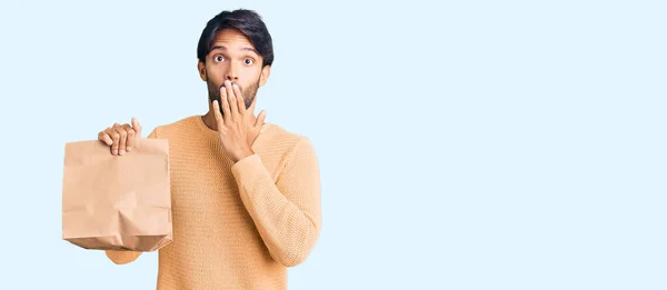 Handsome Hispanic Man Holding Take Away Paper Bag Covering Mouth — Stock Photo, Image