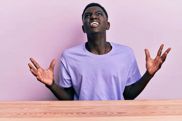 Jovem Afro Americano Vestindo Roupas Casuais Sentado Mesa Louco Louco — Fotografia de Stock