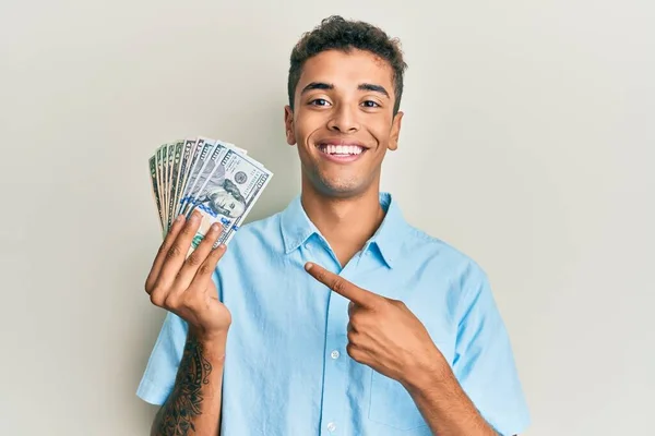Joven Hombre Afroamericano Guapo Sosteniendo Dólares Sonriendo Feliz Señalando Con — Foto de Stock