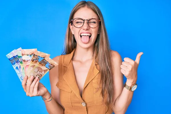Młoda Blondynka Dziewczyna Trzyma Kanadyjskie Dolary Wystający Język Szczęśliwy Śmieszne — Zdjęcie stockowe