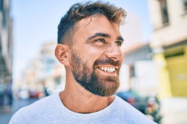 Genç İspanyol adam gülümseyerek şehirde mutlu bir şekilde yürüyor.