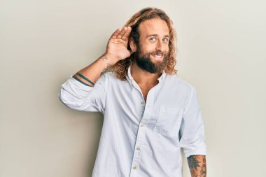 Sakallı, uzun saçlı, sıradan beyaz gömlekli, sırıtan, kulağına fısıldayan ve dedikoduları ve dedikoduları dinleyen yakışıklı bir adam. Sağırlık kavramı. 