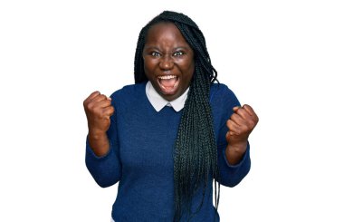 Örgülü, sıradan kıyafetler giyen genç siyahi kadın kollarını kaldırıp, gözlerini açarak başarıyı kutluyor ve şaşırıyor. Kazanan konsept. 