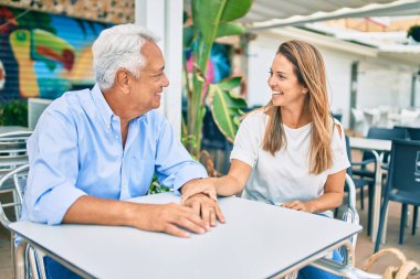 Orta yaşlı çift kahve dükkanının terasında mutlu ve neşeli bir şekilde oturuyor.