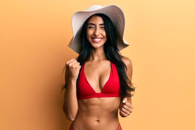 Güzel İspanyol kadın bikini ve yaz şapkası giyerek başarıyı kolları havada ve gözleri kapalı kutluyor. 