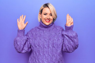 Güzel sarışın ve cüsseli bir kadın mor arka plan üzerine balıkçı yaka kazak giyip dokuz numarayı gösterirken kendinden emin ve mutlu bir şekilde gülümsüyor..