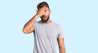 Gündelik kıyafetler giyen genç İspanyol adam şok içinde yüzünü ve gözlerini kapayarak utanmış ifadesiyle parmaklarından bakıyor.. 