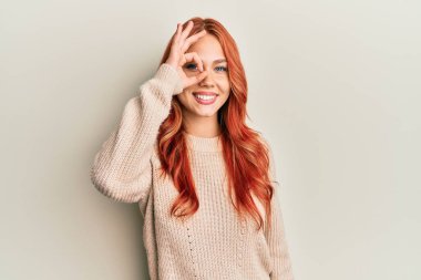 Genç, güzel, kızıl saçlı, sıradan bir kazak giyen, el hareketleriyle gülümseyen, mutlu yüzüyle parmaklarının arasından bakan bir kadın.. 