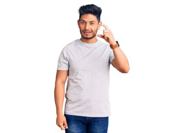 Yakışıklı Latin Amerikalı rahat tişört giyen, gülümseyen, kendine güvenen, el hareketleriyle küçük boy işareti yapan, parmaklarıyla işaret eden ve kameraya bakan genç adam. ölçüm kavramı. 