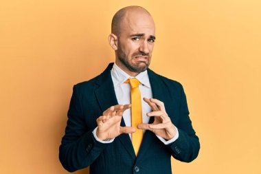 Genç İspanyol bir adam iş elbisesi giyiyor ve iğrenç bir ifade takınıyor. Tiksinti tepkisi yüzünden tiksinmiş ve korkmuş bir ifade takınıyor. Eller havada. 