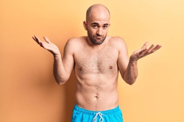 Mayo giyen genç ve kel bir adam. Hiçbir fikrim yok. Mayosuz, bilgisiz ve kolları açık.. 