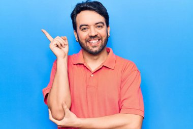 Gündelik kıyafetler giyen genç İspanyol adam gülümsüyor mutlu bir şekilde elini ve parmağını yana uzatıyordu. 