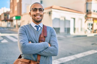 Genç Afrikalı Amerikalı iş adamı gülümseyerek şehirde mutlu bir şekilde yürüyor..