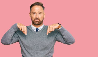 Handsome middle age man wearing business clothes pointing down looking sad and upset, indicating direction with fingers, unhappy and depressed. 