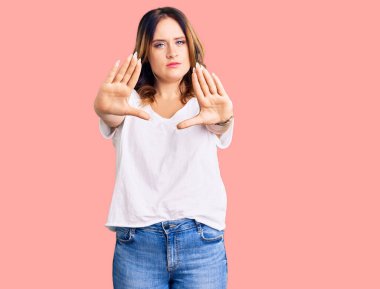 Beyaz günlük tişört giyen, el ve parmaklarıyla çerçeve yapan beyaz, güzel bir kadın. 