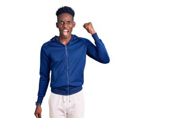 Genç Afro-Amerikan erkek spor giysisi giyiyor kızgın ve kızgın yumruk kaldırıyor öfkeyle bağırırken. öfke ve agresif konsept. 