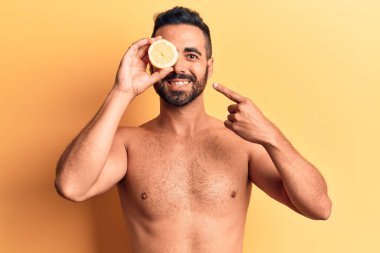 İspanyol asıllı genç adam limonsuz duruyor. Gülümsüyor, mutlu bir şekilde elini ve parmağını gösteriyor. 