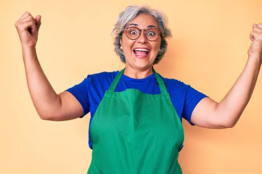 Önlük ve gözlük takan son sınıf İspanyol kadın gururla haykırıyor, zaferi kutluyor ve başarıyı kollarını kaldırarak heyecanlanıyor. 