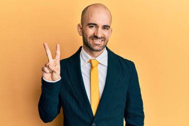 Genç İspanyol takım elbiseli ve kravatlı adam kendini beğenmiş ve mutlu bir şekilde gülümserken iki numarayı gösterip işaret ediyor.. 