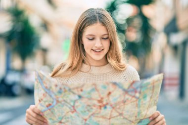 Güzel Kafkasyalı turist gülümseyerek şehirde mutlu bir harita tutuyor..