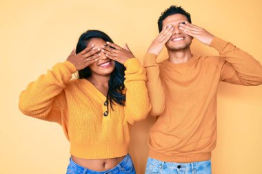 Güzel, Latin, genç bir çift, günlük giysiler giyip, gözleri kapatıyorlar, neşeli ve komik gülümsüyorlar. kör kavram. 