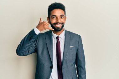 Sakallı, takım elbiseli ve kravatlı yakışıklı, telefonla el ve parmak hareketi yapan telefonda konuşur gibi gülümseyen bir adam. iletişim kavramları. 