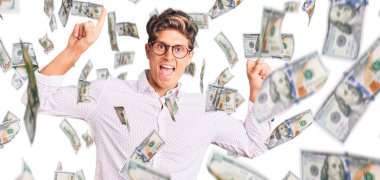 İş kıyafetleri ve gözlük takan genç yakışıklı adam şaşırmış, şaşırmış ve parmaklarıyla işaret ederek kollarını kaldırmış..