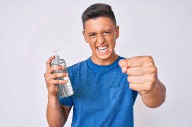 El dezenfektanı kullanan genç İspanyol çocuk öfkeyle bağırıyor, öfkeyle bağırıyor ve el kaldırıyor. 