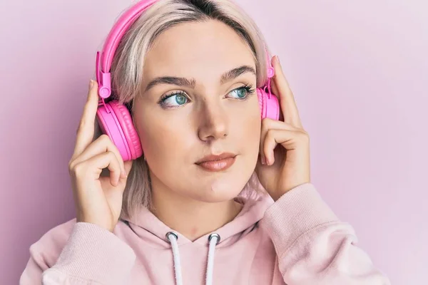 Ung Blond Flicka Lyssnar Musik Med Hörlurar Ler Tittar Sidan — Stockfoto