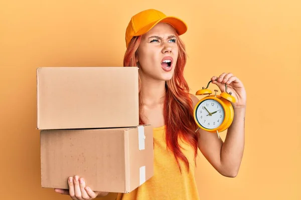 Young Redhead Woman Holding Delivery Package Alarm Clock Angry Mad — 图库照片