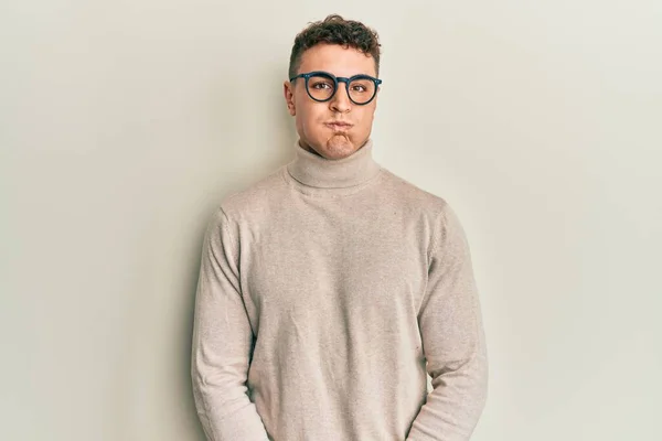 Hispanic Young Man Wearing Casual Turtleneck Sweater Puffing Cheeks Funny — 스톡 사진