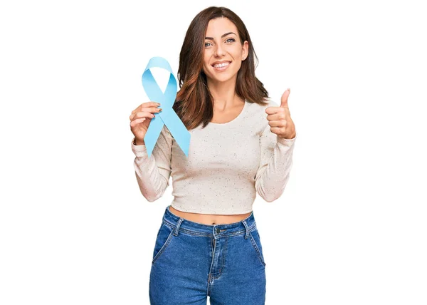 Młoda Brunetka Kobieta Trzyma Niebieską Wstążkę Uśmiechnięta Szczęśliwy Pozytywny Kciuk — Zdjęcie stockowe