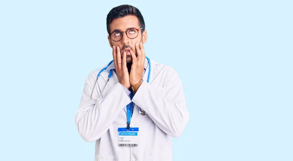 Jovem Hispânico Vestindo Uniforme Médico Estetoscópio Mãos Cansadas Cobrindo Rosto — Fotografia de Stock