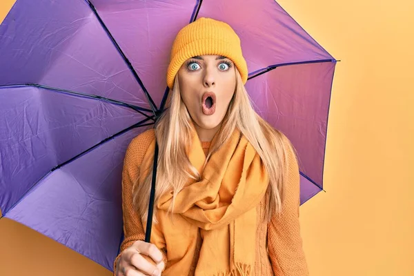 若いです白人女性を保持紫色の傘怖がってと驚きのために口を開けて驚きます 不信顔 — ストック写真