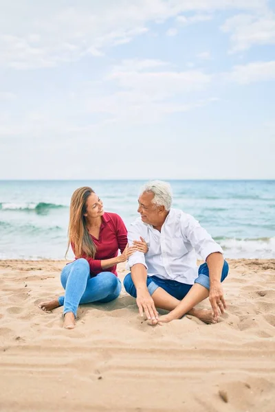 Latynoska Para Średnim Wieku Uśmiecha Się Szczęśliwa Przytula Siedząc Plaży — Zdjęcie stockowe