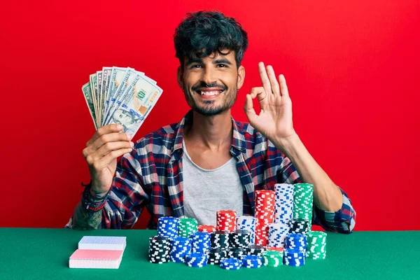 Jovem Hispânico Sentado Mesa Com Fichas Poker Cartas Segurando Dólares — Fotografia de Stock