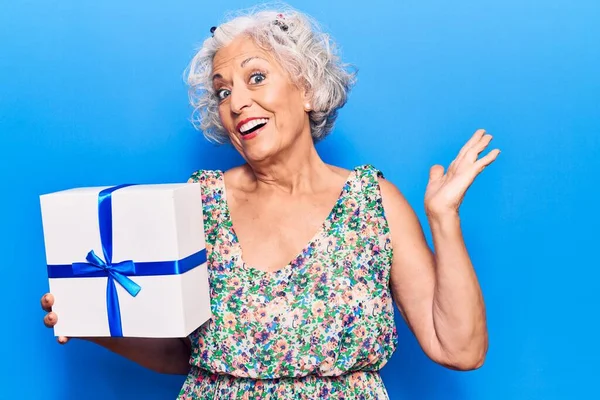 Mulher Cabelos Grisalhos Sênior Segurando Presente Celebrando Realização Com Sorriso — Fotografia de Stock